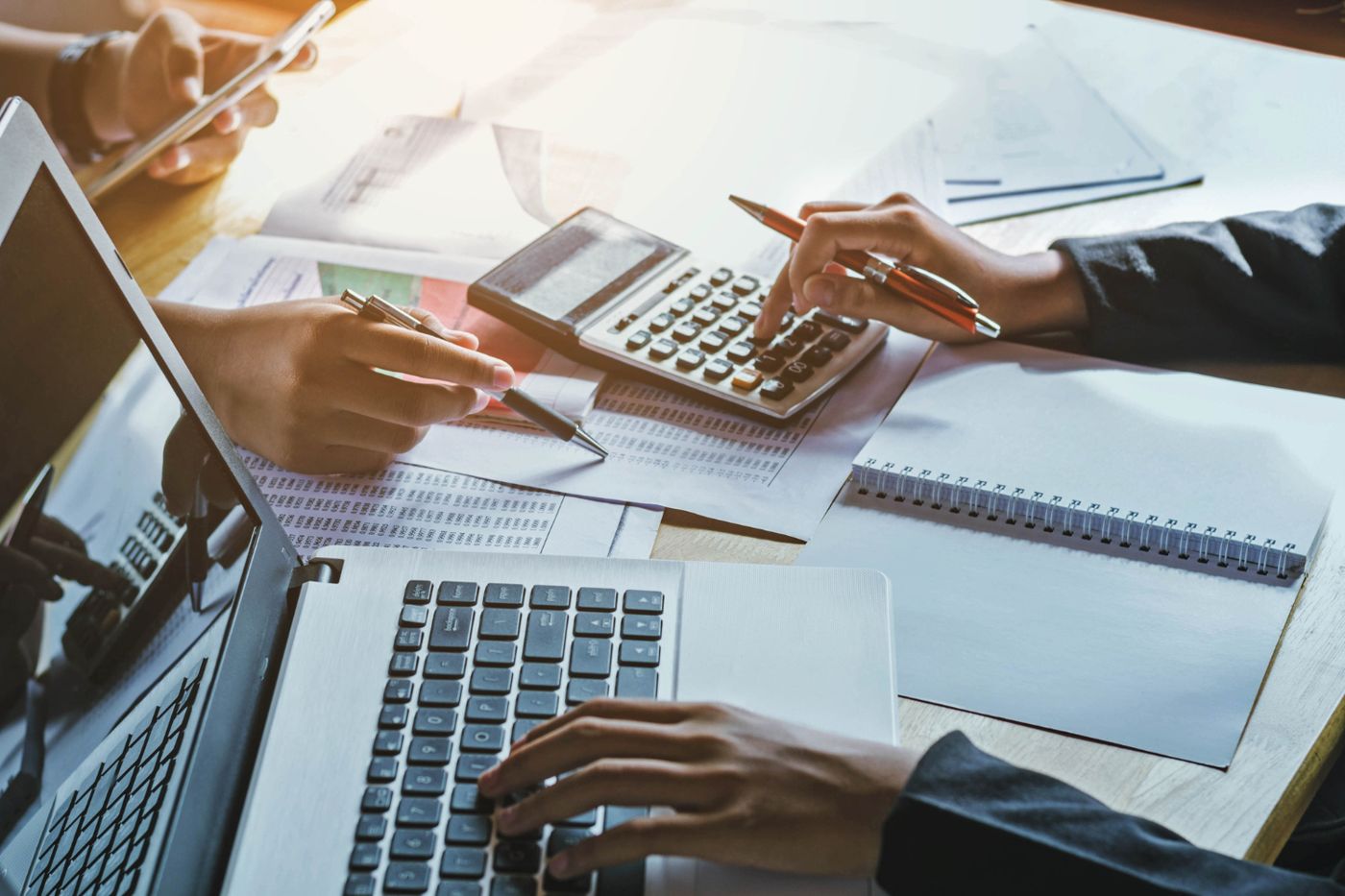 A finance team reviewing figures with a calculator and laptop